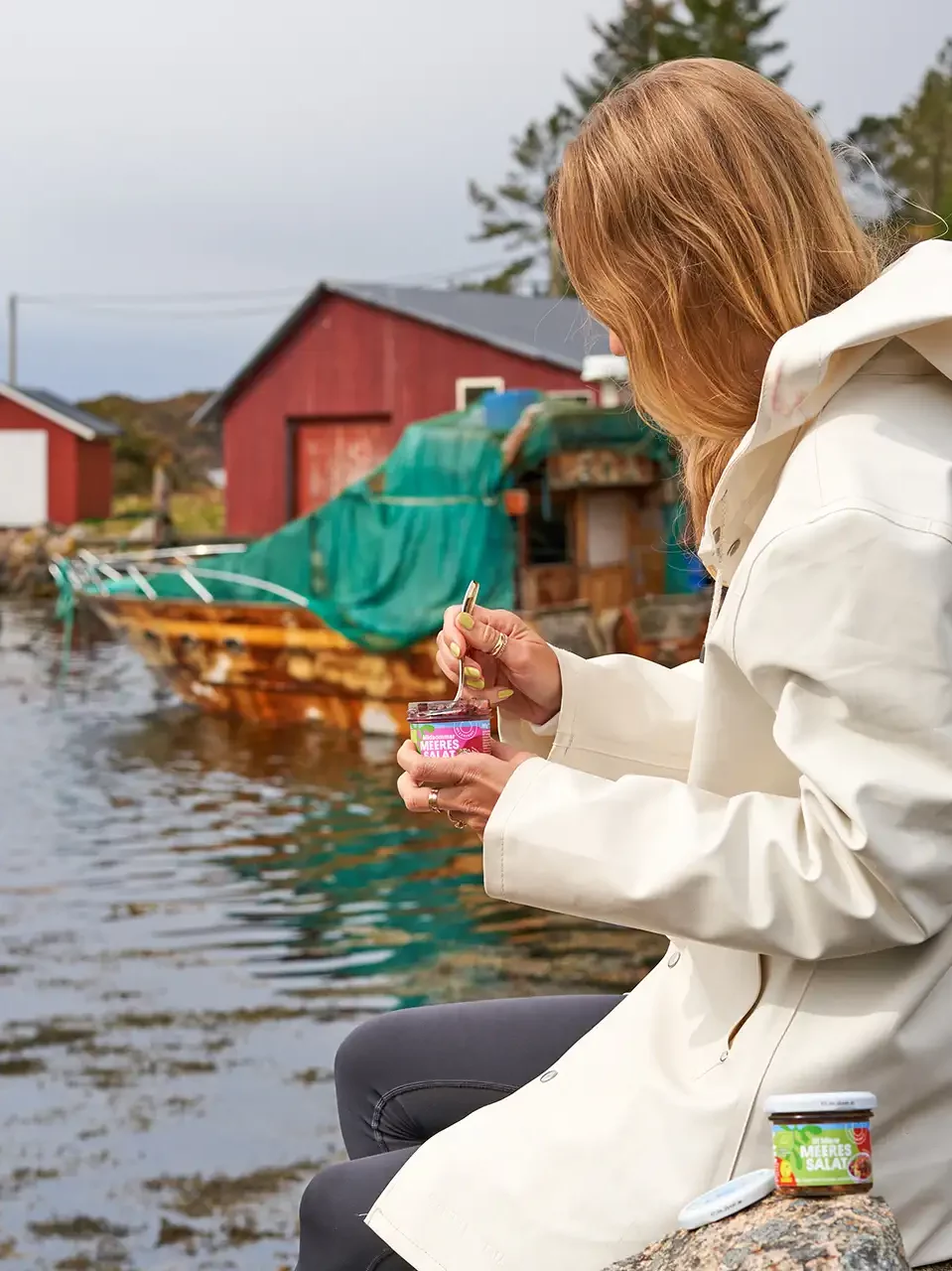 Blonde Frau isst Meeressalat am Wasser in Norwegen